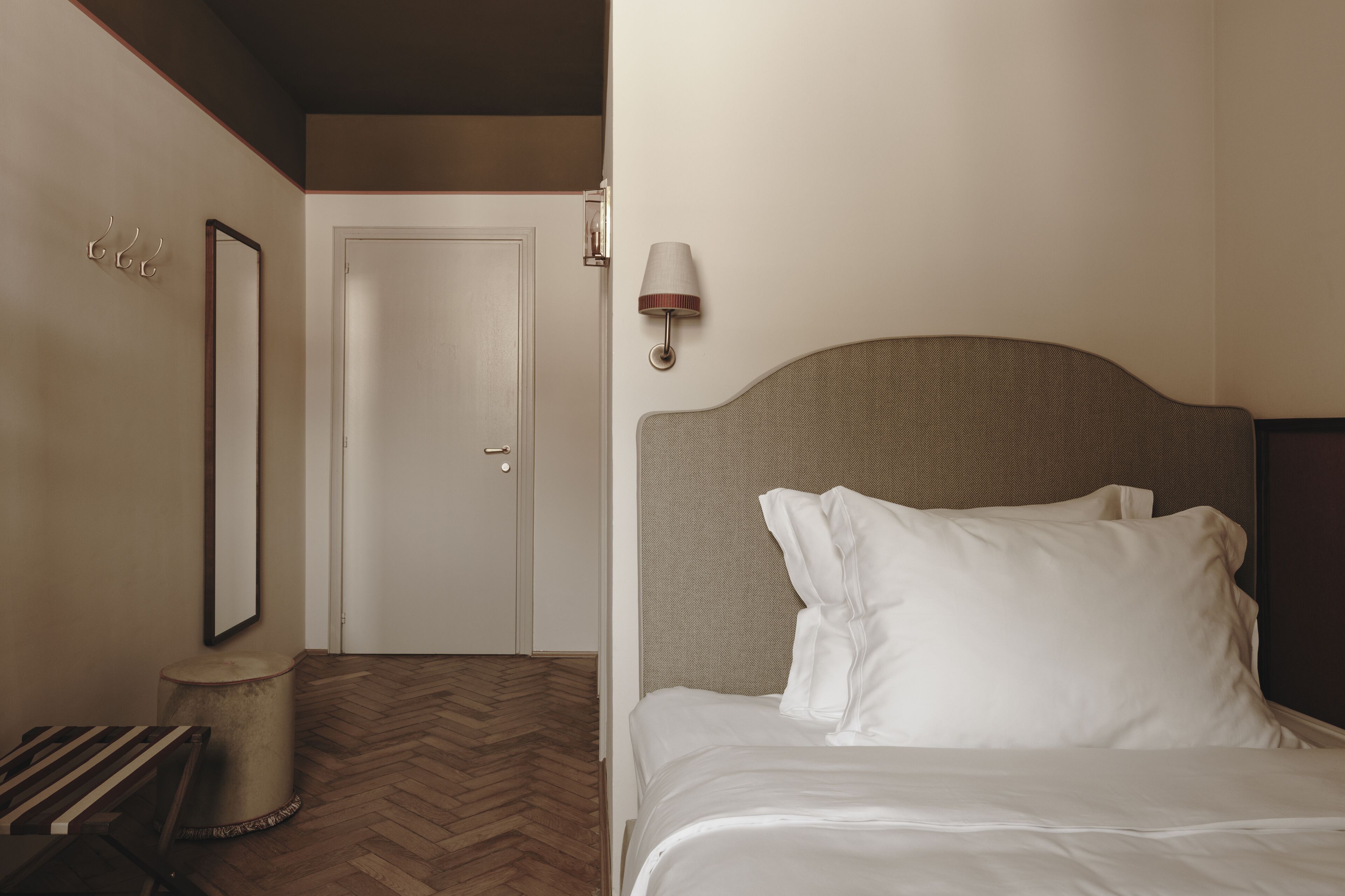 Una habitación de hotel con una cama, una silla, una lámpara y una puerta.