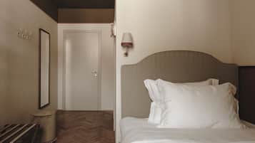Una habitación de hotel con una cama, una silla, una lámpara y una puerta.