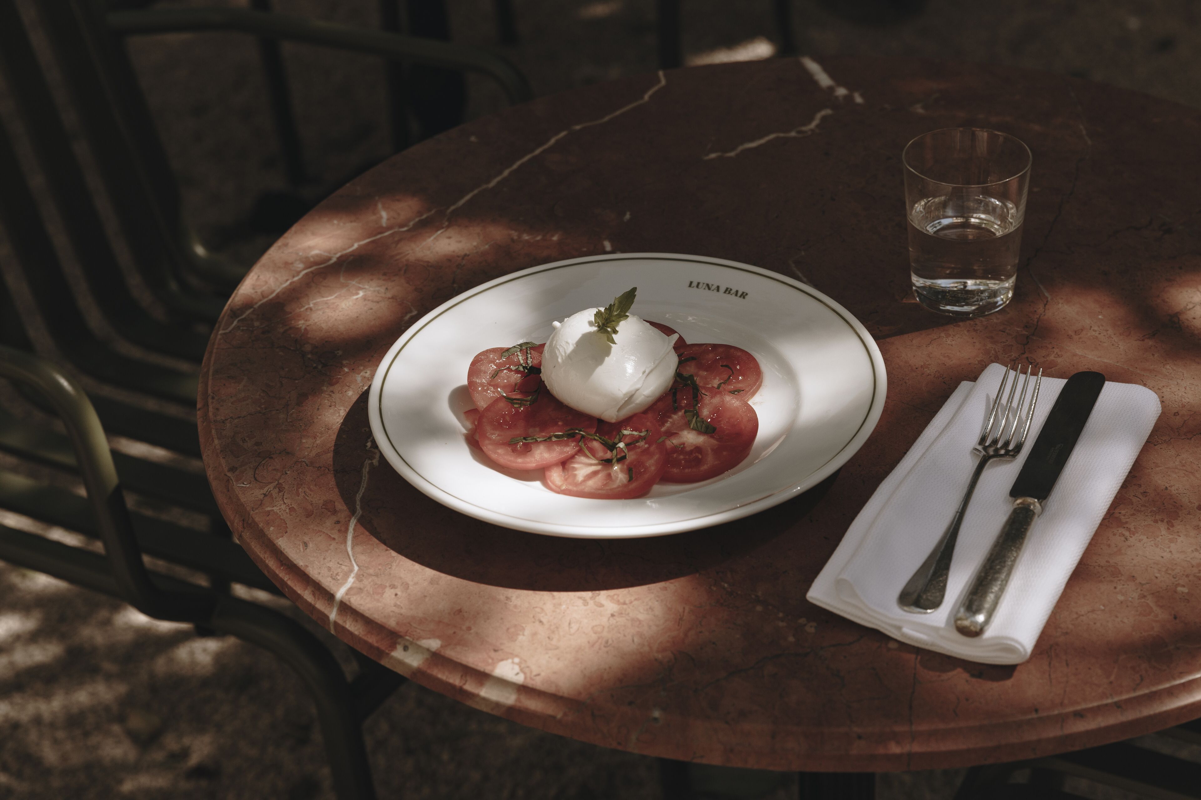 A table with a plate of food, a glass of water, and cutlery.