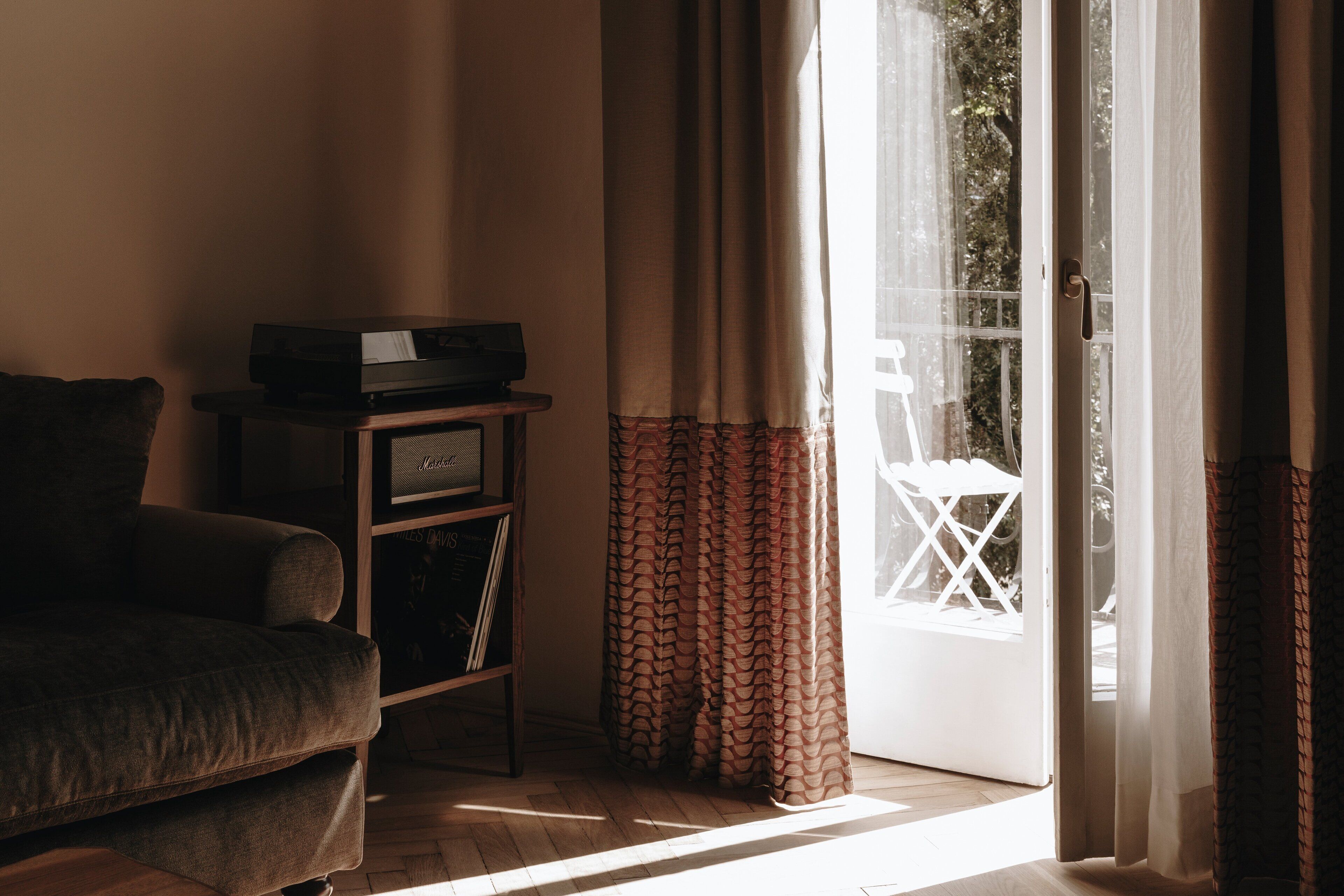Sala de estar con sofá, una mesita y televisor. Cuenta con una puerta corrediza de vidrio que da a un espacio exterior.