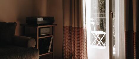 Sala de estar con sofá, una mesita y televisor. Cuenta con una puerta corrediza de vidrio que da a un espacio exterior.