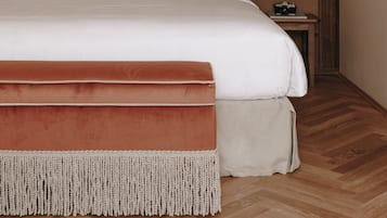 A neatly made bed with a red headboard, a bedside lamp, and a camera on a small table beside it.