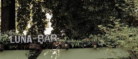 A Luna Bar with a wooden exterior, a green awning, and bookshelves filled with books and magazines.