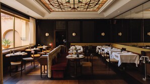 Un restaurant avec des tables rondes, des boiseries sombres et un plafond en vitrail.