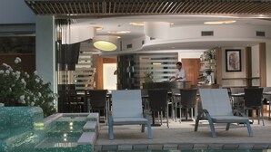 A poolside area with lounge chairs, a bar, and a kitchen visible in the background.