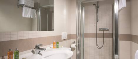 A modern bathroom with a glass-enclosed shower, a double sink, and a toilet.