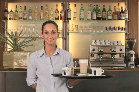 A bar area with a variety of liquor bottles and glasses on shelves.
