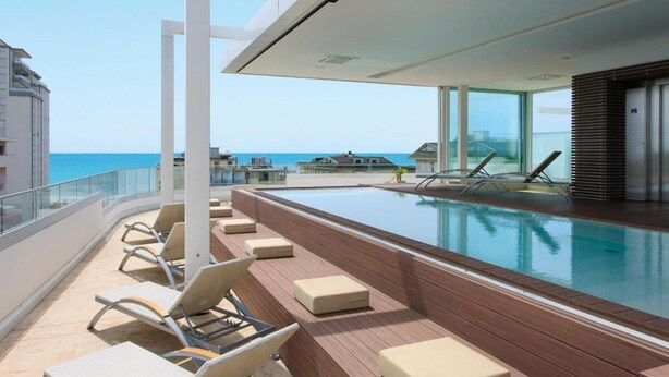 A poolside area with lounge chairs and a view of the sea.
