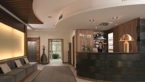 A modern reception area with a curved reception desk, a sofa, and a large vase of flowers.