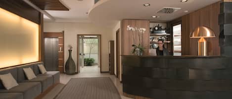 A modern reception area with a curved reception desk, a sofa, and a large vase of flowers.
