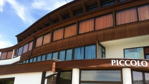 A building with a wooden facade and a sign that reads "PICCOLO". - Piccolo Hotel Sciliar (Castelrotto)