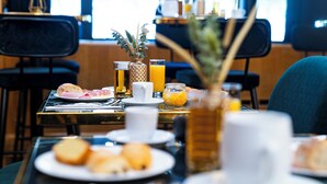 A breakfast setting with plates of food, glasses of orange juice, and a vase with greenery. - Hotel Le Cercle Tour Eiffel (Paris)