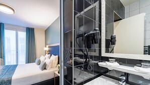 A modern hotel room with a large bed, a bathroom with a black tiled shower, a white sink, and a large mirror. - Hotel Le Cercle Tour Eiffel (Paris)