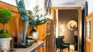 A hallway with wooden paneling, a green chair, a vase with flowers, and a statue. - Hotel Le Cercle Tour Eiffel (Paris)