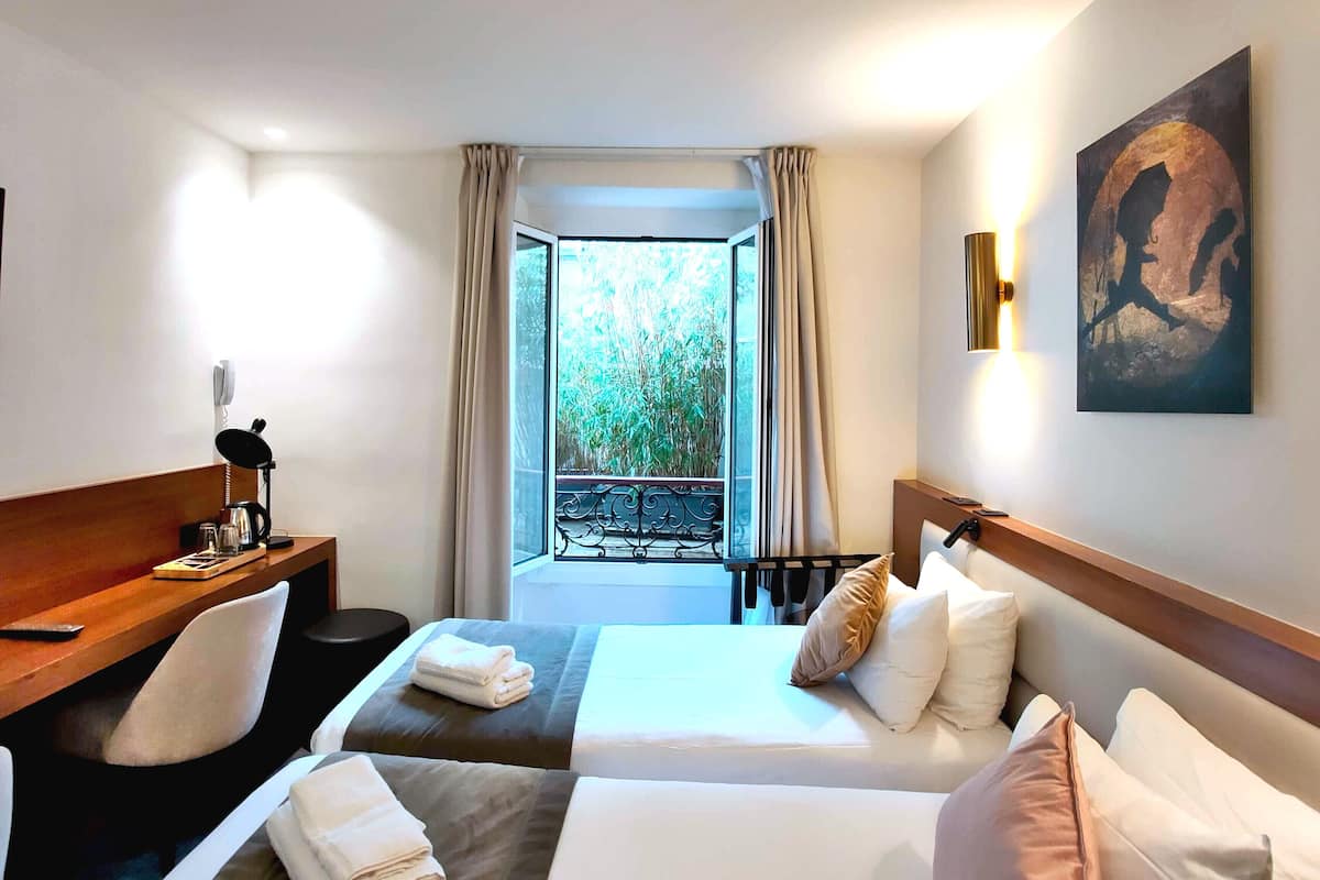 Habitación de hotel con dos camas, un escritorio, un teléfono y un cuadro.