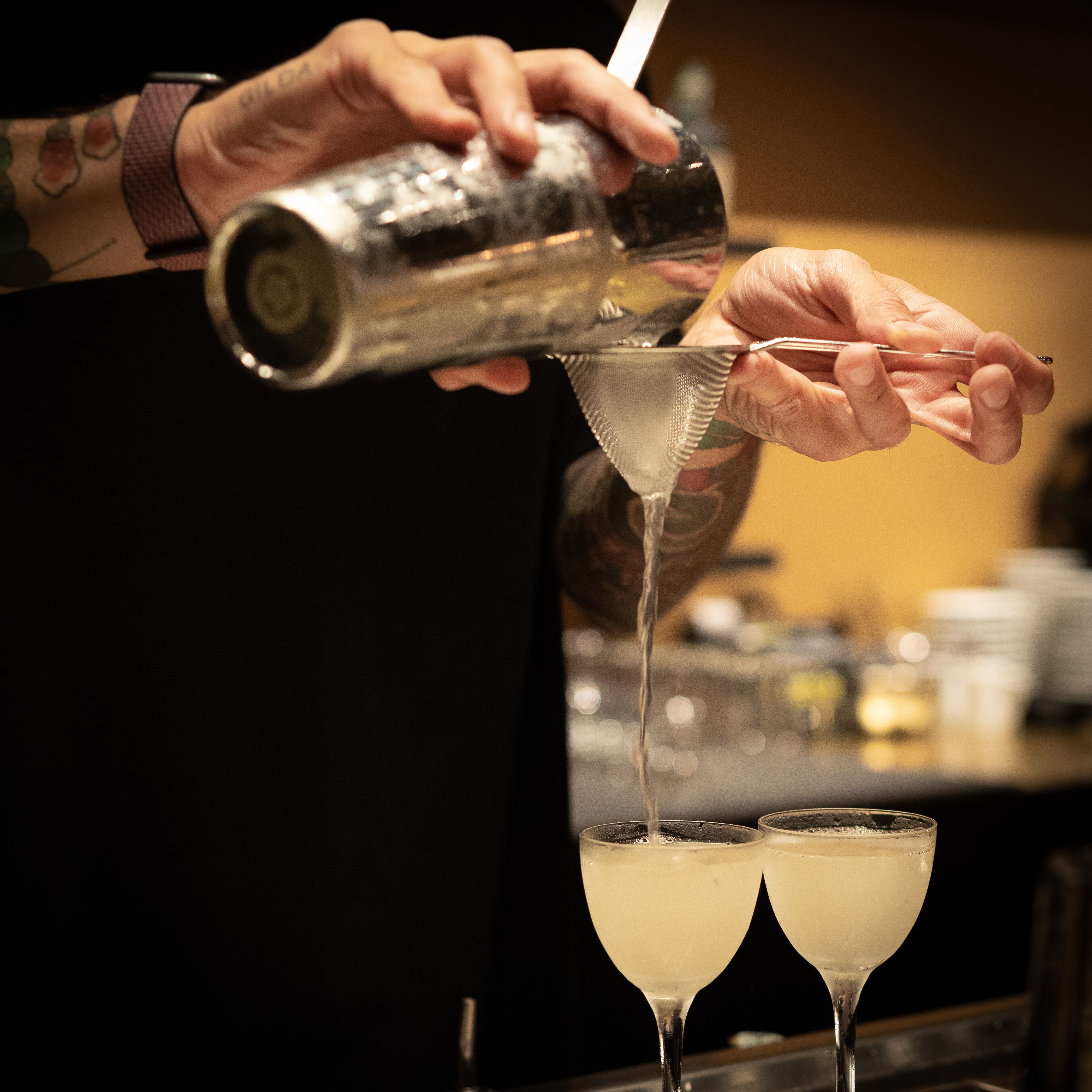 A person pouring a drink into a martini glass.