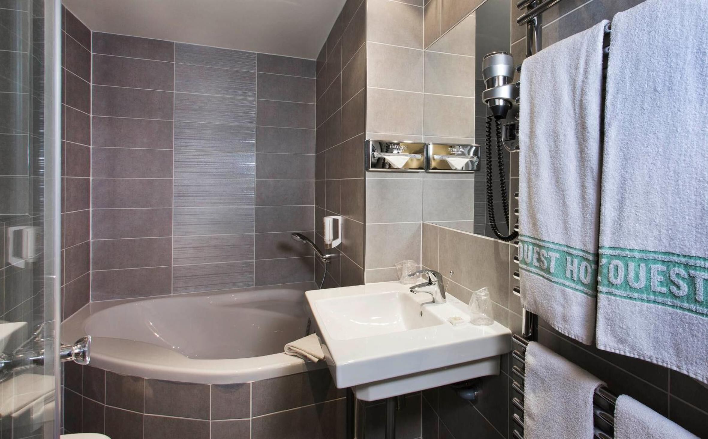 Un baño moderno con bañera, lavamanos y un perchero para toallas.