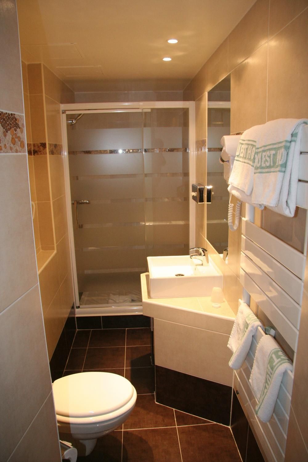 A bathroom with a shower, toilet, sink, and towel rack.