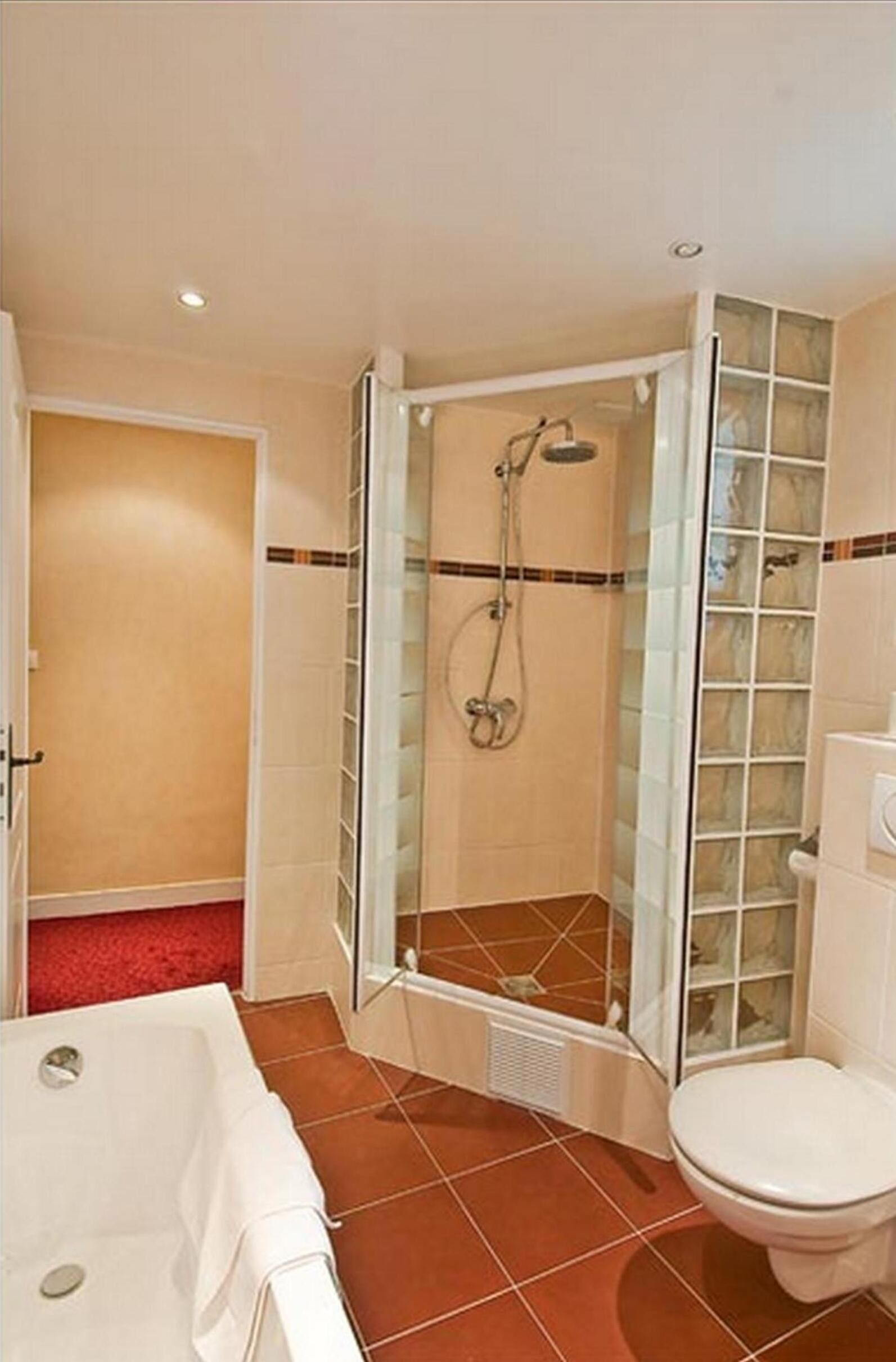A bathroom with a glass-enclosed shower, a bathtub, and a toilet.