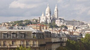 A cityscape with a prominent white building with domes in the background. - Hotel Léna Paris (Paris)