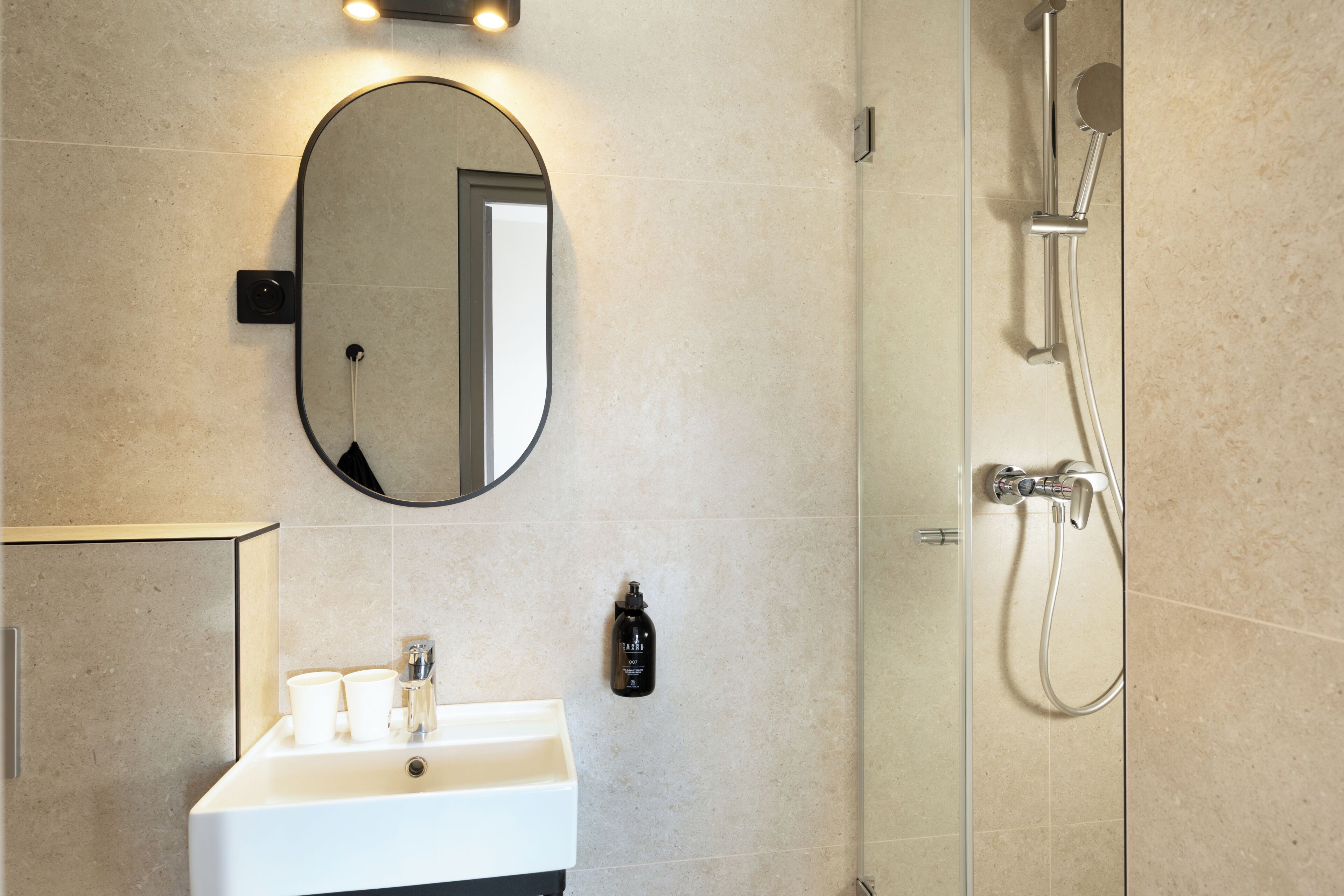A bathroom with a sink, mirror, and shower.