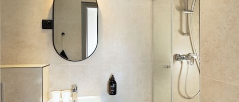 A bathroom with a sink, mirror, and shower.