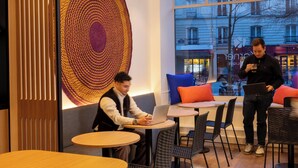 Un intérieur moderne avec des tables rondes, des chaises noires et une grande œuvre d’art circulaire accrochée au mur.