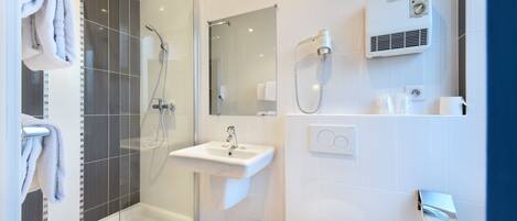 Un baño moderno con ducha envuelta en vidrio, lavabo blanco y retrete.