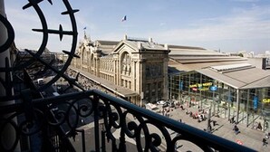 Una estación de tren con un amplio edificio de cristal que muestra el letrero "GAME DU NORD" y un edificio histórico al fondo.