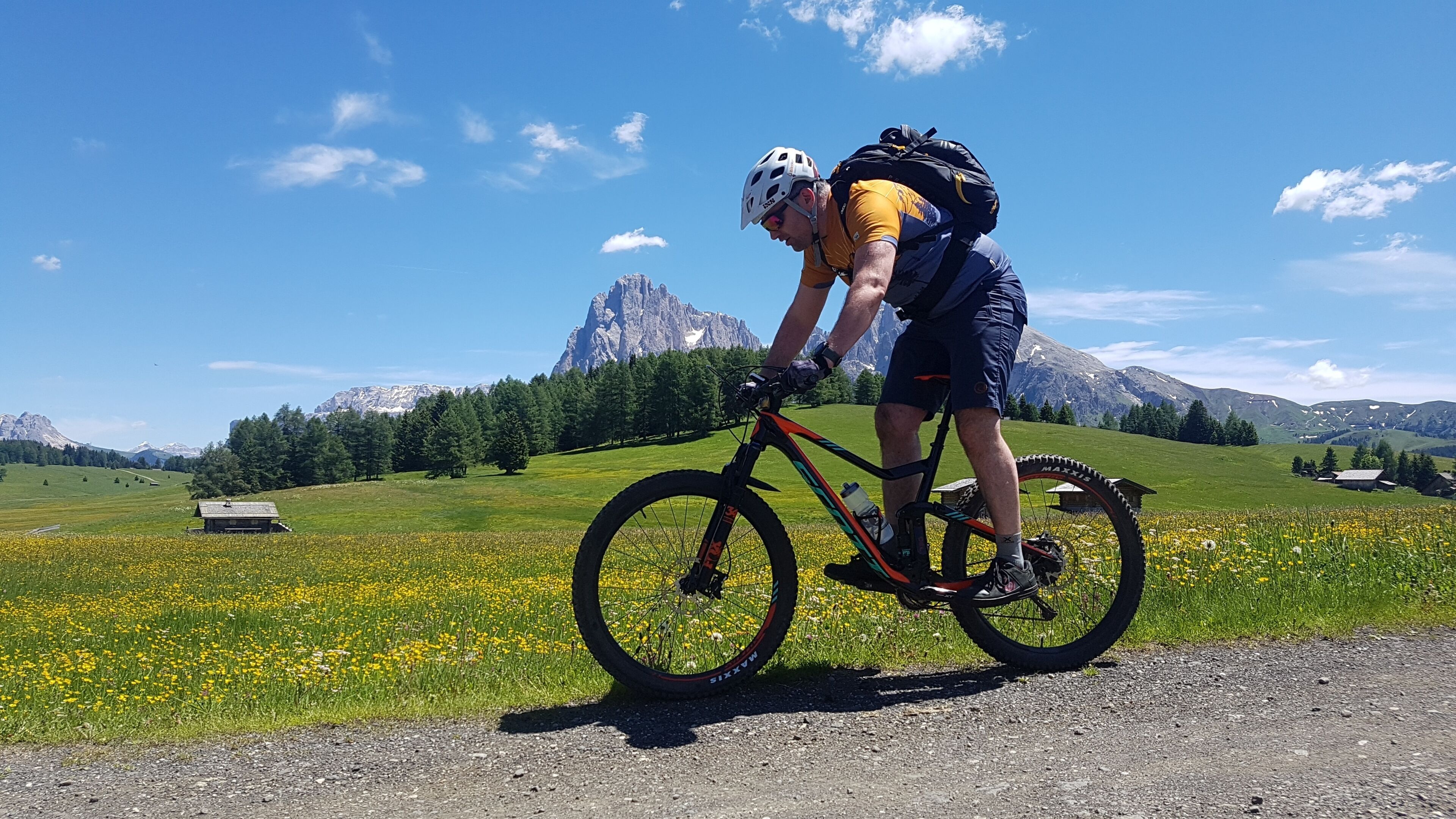 Ein Radfahrer auf einer Straße vor einer gebirgigen Landschaft.