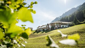 A hillside property with multiple buildings, including a large house with a sloped roof and a smaller structure with a balcony. - Hotel Digon (Castelrotto)