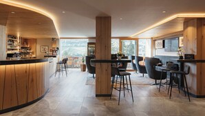 A modern bar area with wooden accents, a bar counter, and seating. - Hotel Digon (Castelrotto)