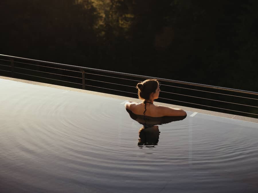 Una piscina al aire libre, sombrillas, sillones reclinables de piscina
