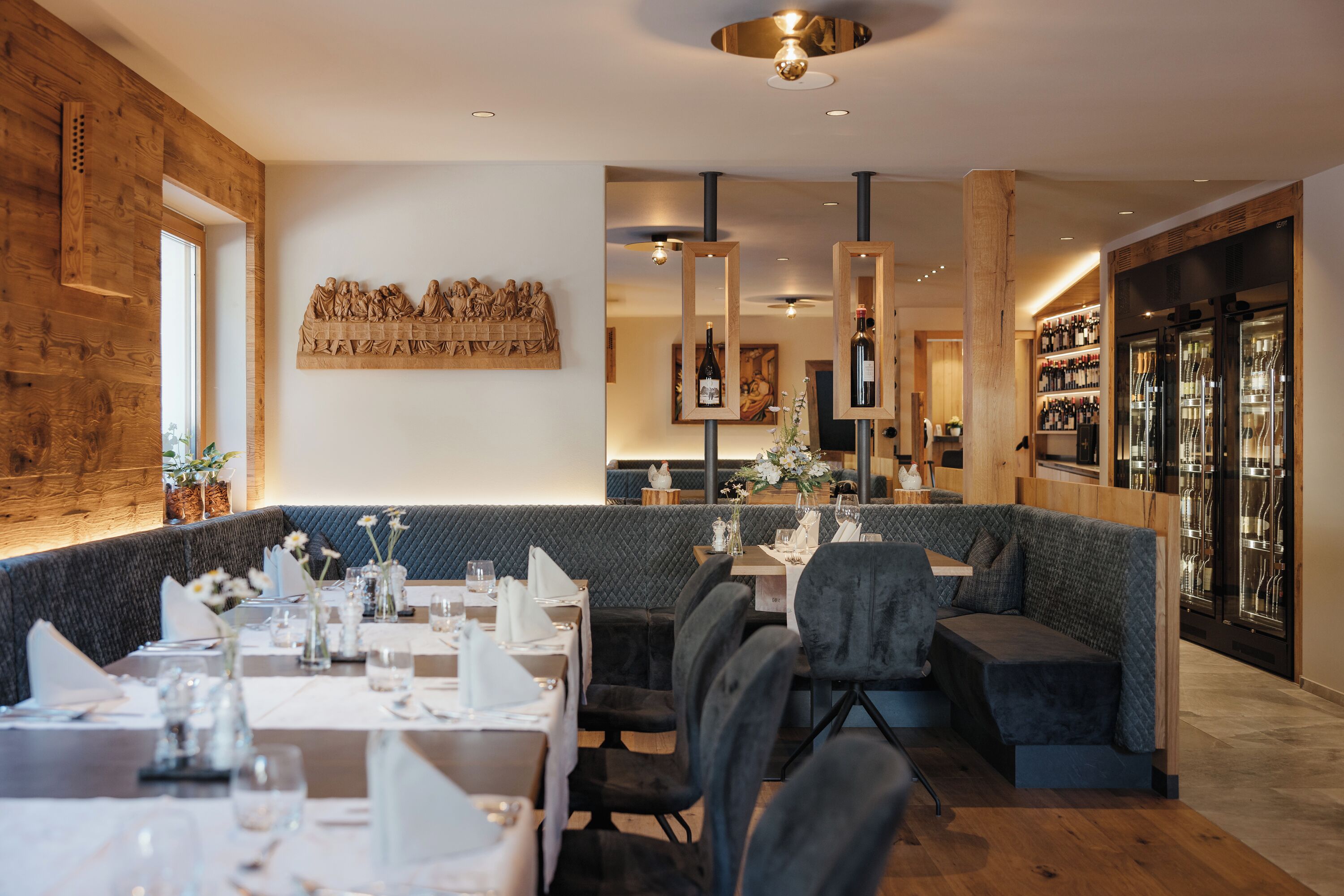 Een restaurant met houten details, een hoge plafond en een wijnrek.