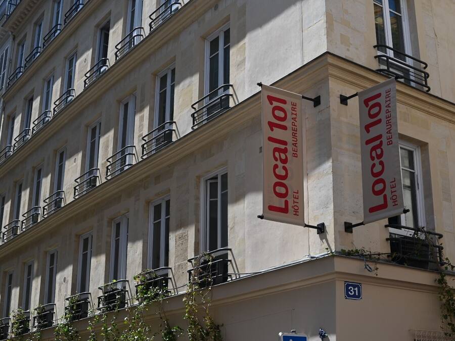 A building with multiple windows and balconies, each with metal railings. There are two large banners hanging from the building's corner, advertising 'Local 101 Hotel Beaurepaire.'