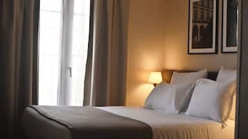 Ein Hotelzimmer mit einem Bett, Vorhängen, einer Lampe und zwei gerahmten Bildern an der Wand.