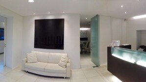A modern reception area with a glass counter, a white sofa, and a large abstract painting on the wall. - Soggiorno Lo Stellino (Siena)