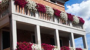 A multi-story building with balconies adorned with flower boxes containing pink and white flowers. - Soggiorno Lo Stellino (Siena)