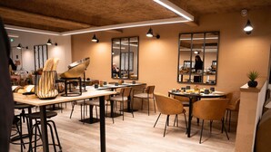 A modern dining area with wooden tables, black metal chairs, and pendant lighting.