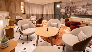 A modern living room with a sofa, chairs, a round table, and a large cityscape mural on the wall.