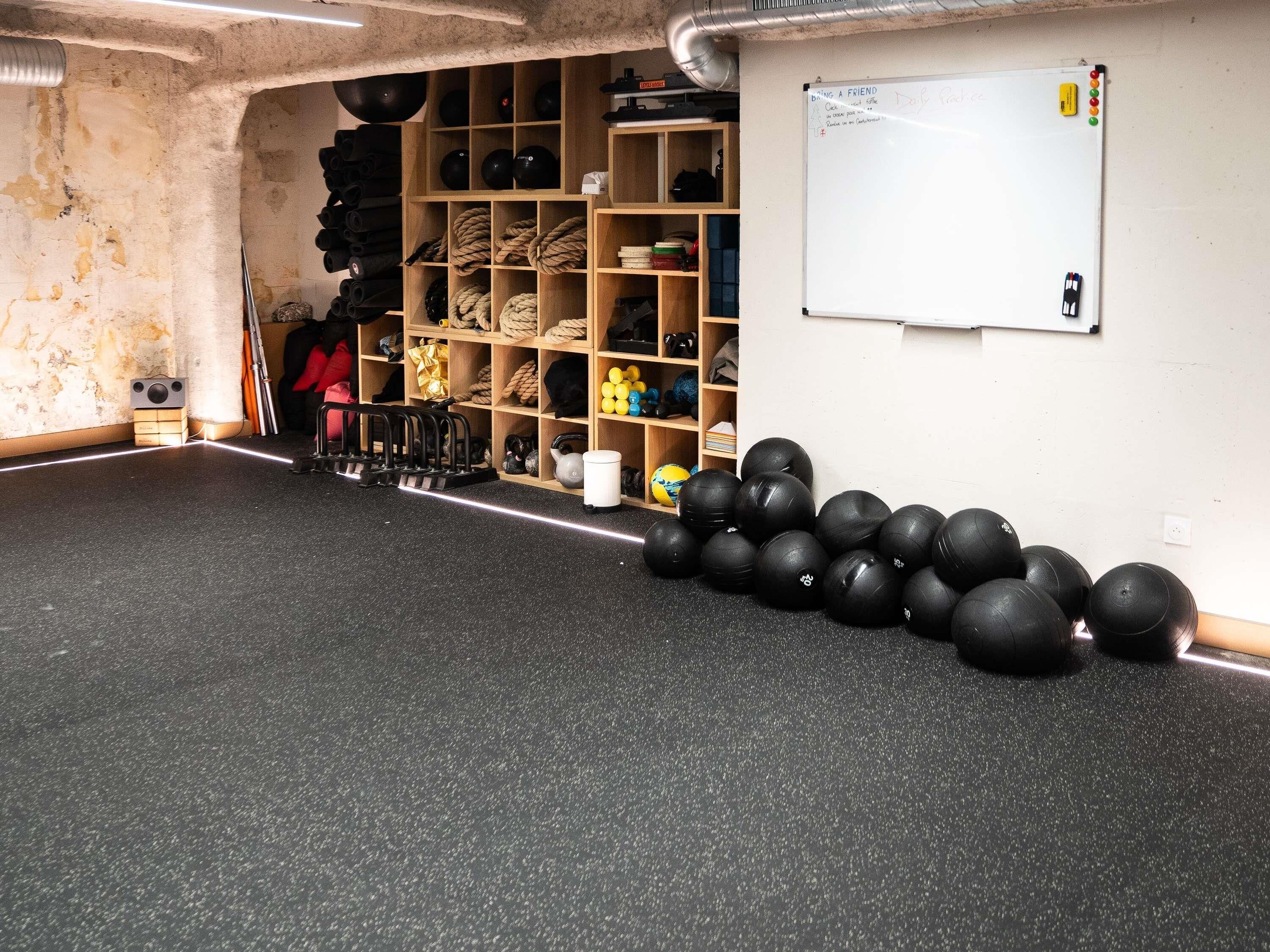 A gym with exercise equipment, a whiteboard, and a storage area with various items.