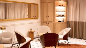 A modern room with a large mirror, wooden wardrobe, and seating area with chairs and a small table.