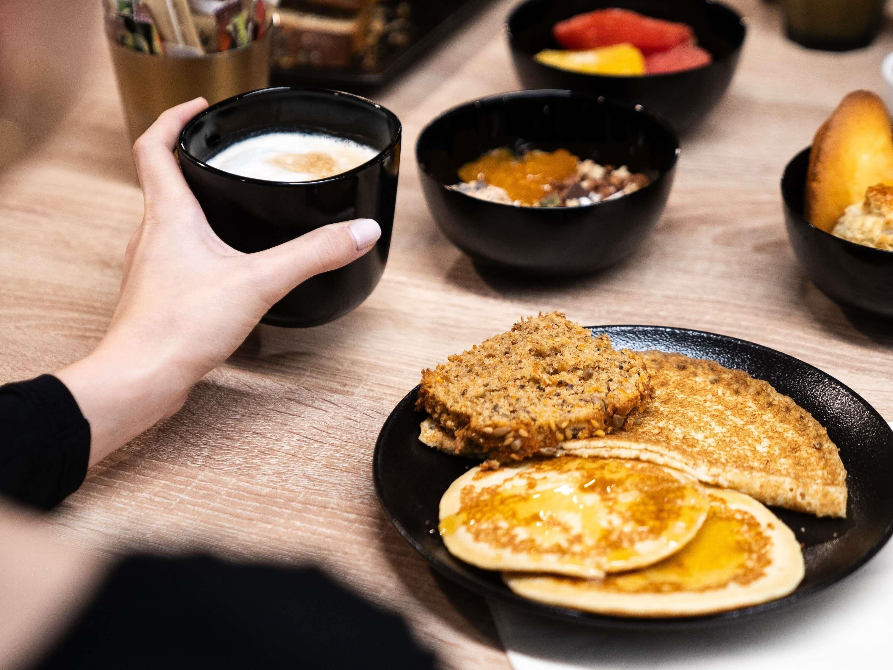 A breakfast setting with a plate of pancakes, a slice of toast, and a cup of coffee.
