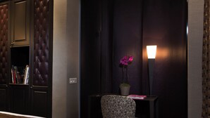 A hotel room with a bed, a small desk with a chair, a potted plant, and a lamp. - Hôtel du Prince Eugène (Paris)