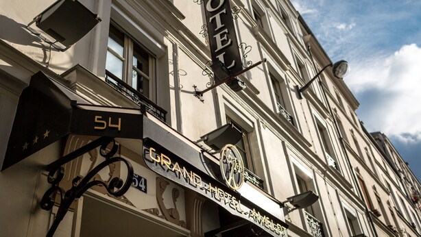 Et hotelskilt med navnet "GRAND HOTEL AMEGALE" og nummeret "54" på bygningens facade.