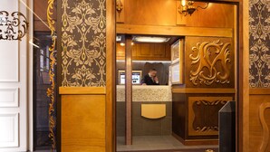 Et receptionområde med en trædisk, garderobe og en dekorativ væg med blomstermønster.