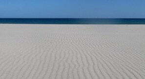 A sandy beach with gentle ripples, leading to a calm sea under a clear sky. - Agriturismo Torre Del Golfo (Cropani)