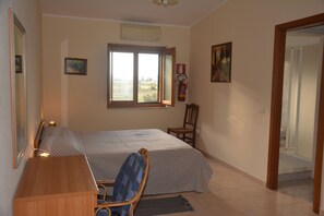 A bedroom with a bed, a desk, a chair, a window, and a door. - Agriturismo Torre Del Golfo (Cropani)