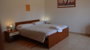 Una cama bien hecha con sábanas blancas, un cabecero de madera y dos mesitas de noche con lámparas.