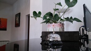 A room with a desk, a computer, a vase with flowers, and a framed picture on the wall. - Le Rose (Tivoli)